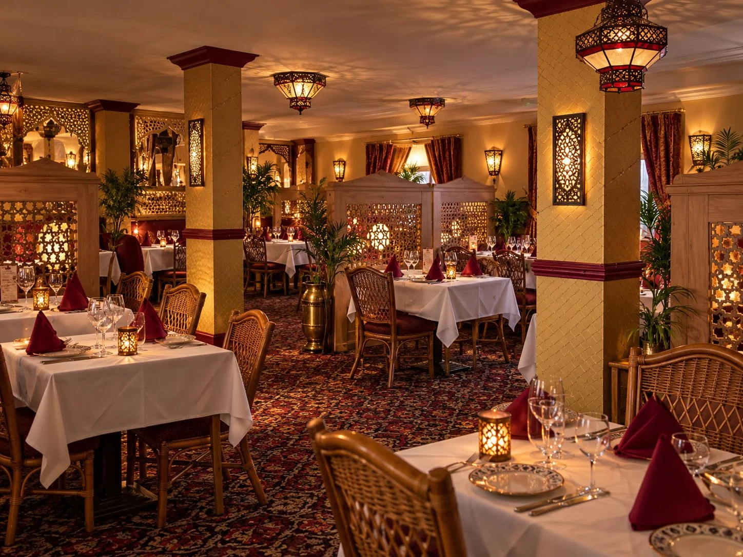 The Amantola dining room by candlelight, tables laid with white linen, wine glasses and folded napkins