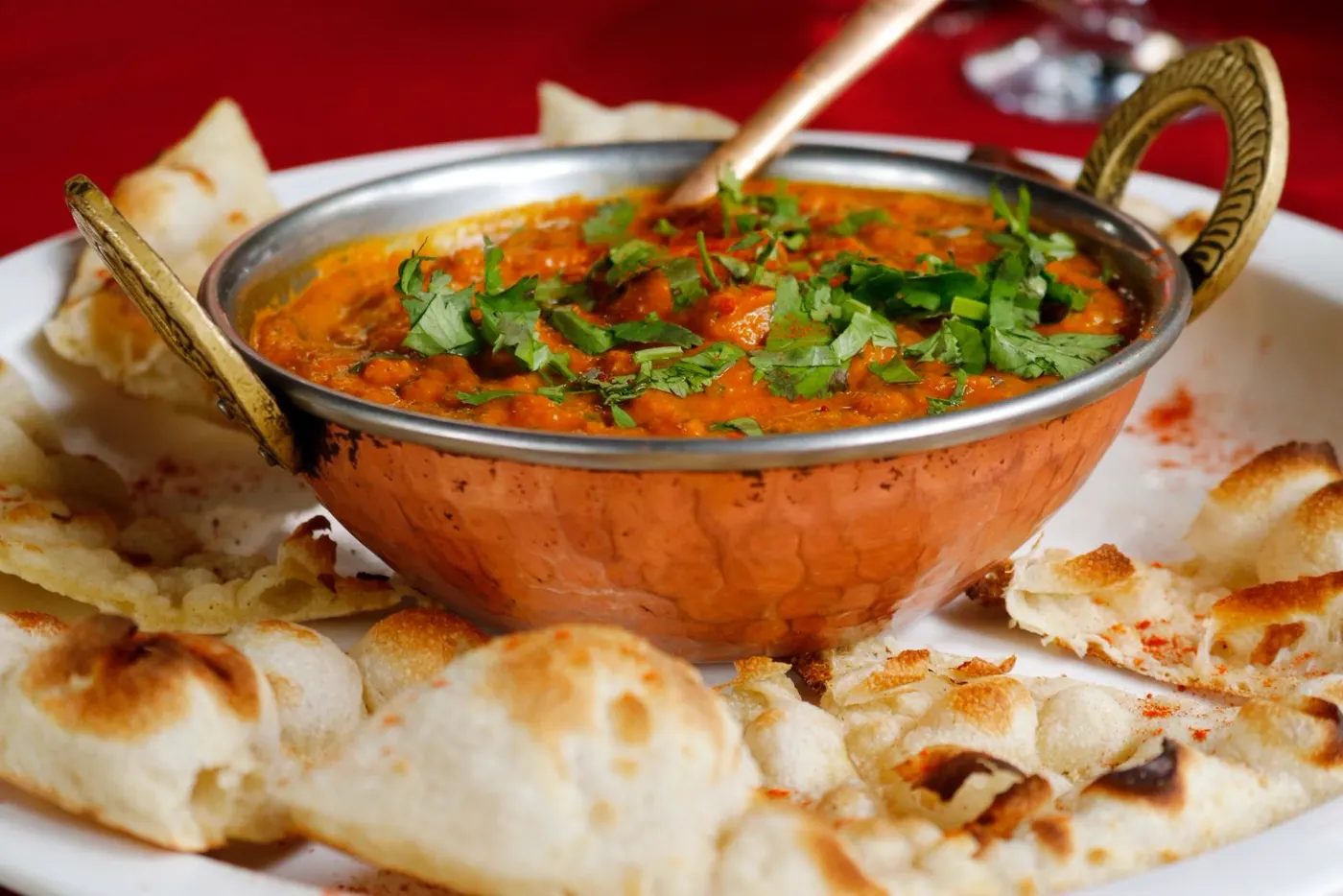 Indian curry served in a copper karahi with fresh naan bread