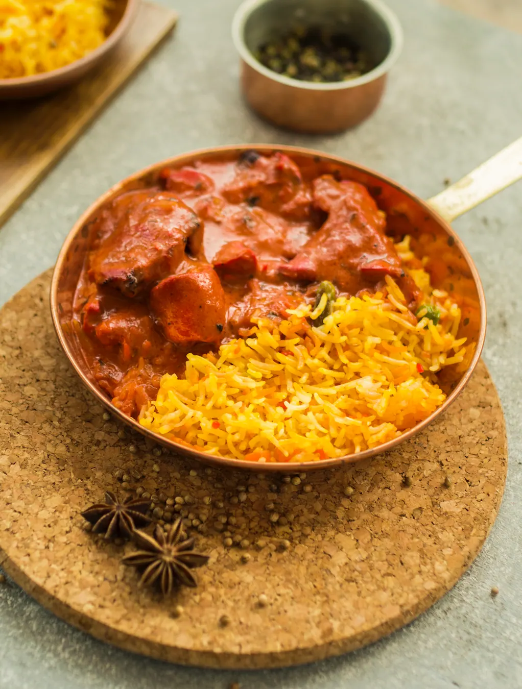 Tandoori chicken tikka masala with spiced pilau rice in a copper pan