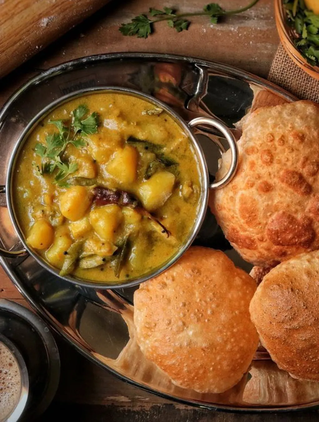 Potato and green bean curry in a balti dish with fried puri breads