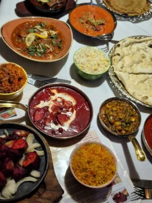 An overhead spread of curries, naan, pilau rice and a sizzling platter