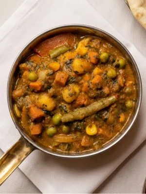 Mixed vegetable curry in a copper pan