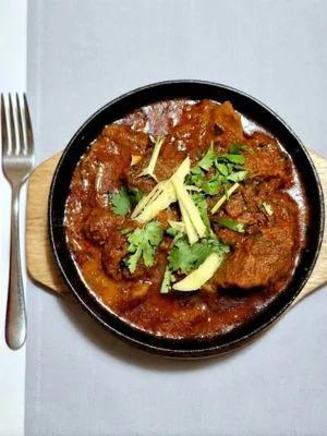 Sizzling lamb curry on a wooden board